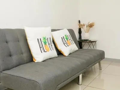 a gray couch with two pillows on top of it at PURA VIDA AIRPORT STAY FREE SHUTTLe in Alajuela City