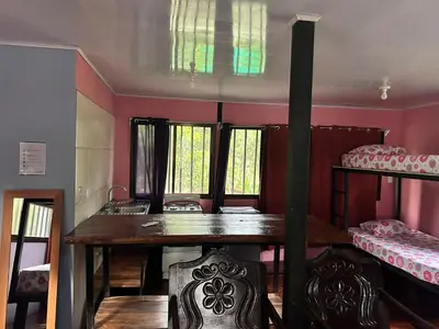 a room with a table and two bunk beds at Hospedaje el Argentico in Tapantí