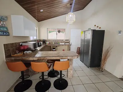 a kitchen with a large counter with orange bar stools at Casa Tribu in Agujas