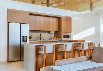 a kitchen with a bar with chairs and a couch at Nimbu East in Tamarindo