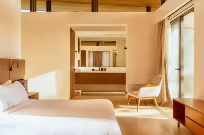 a bedroom with a bed and a chair and a bathroom at Nimbu East in Tamarindo