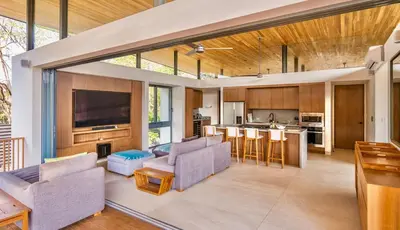 an open living room and kitchen with a couch and chairs at Nimbu East in Tamarindo