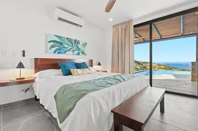 a bedroom with a large bed with a view of the ocean at Villa Costa Sota - Ocean View & Pickleball Courts in Coco