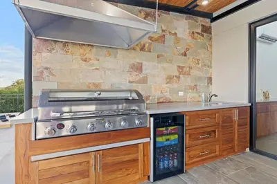 a kitchen with a stove and a stone wall at Villa Costa Sota - Ocean View & Pickleball Courts in Coco