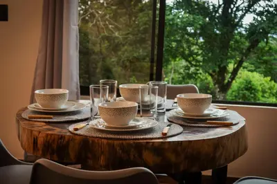 a wooden table with cups and plates on it with a window at Divan Jungle Lodge in Fortuna