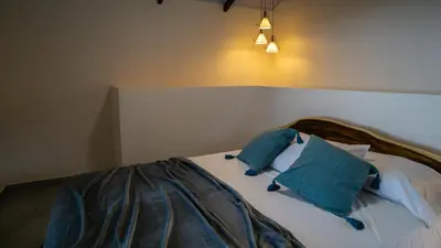 a bed with two blue pillows on top of it at Divan Jungle Lodge in Fortuna