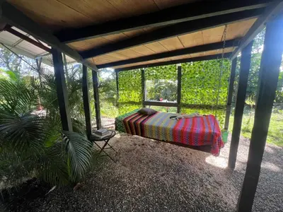 a covered porch with a bed and a chair at Cabañita tipo Chalet in Fortuna