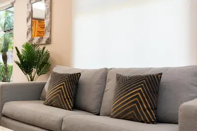 a couch with two pillows on it in a living room at Jacó Cozy 1BR Pool AC Secure Near Beach in Jacó