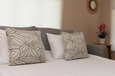 a bed with white pillows and a gray couch at Jacó Cozy 1BR Pool AC Secure Near Beach in Jacó