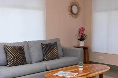 a living room with a gray couch and a table at Jacó Cozy 1BR Pool AC Secure Near Beach in Jacó