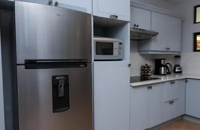 a stainless steel refrigerator in a kitchen with white cabinets at Corteza 2BD Gated AC Quiet Terrace Pools in Jacó
