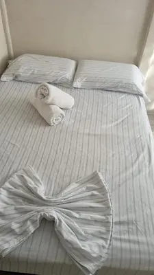 a white bed with two towels and a bow on it at Casas de Playa en Familia