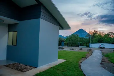 a blue house with a yard and a driveway at Villa Elemental Modern Villa Volcano Views & Luxe Touches in Fortuna