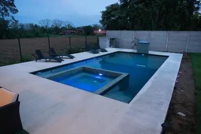 a swimming pool in a yard with two chairs at Villa Elemental Modern Villa Volcano Views & Luxe Touches in Fortuna