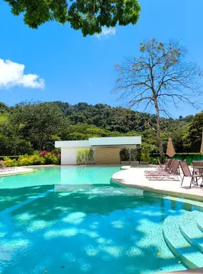a swimming pool with chairs and a building at Luxury condo in Selva Coral Jacó Beach in Jacó
