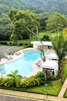 an overhead view of a pool with chairs and trees at Luxury condo in Selva Coral Jacó Beach in Jacó