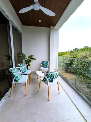 a porch with chairs and a table and a ceiling fan at Luxury condo in Selva Coral Jacó Beach in Jacó