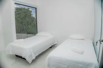 two beds in a white room with a window at Villa Sunset Relaxing 2BR Villa with Outdoor Hot Tub in Fortuna