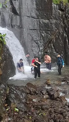 a group of people standing in front of a waterfall at Rio Paquita Lodge in Tapantí