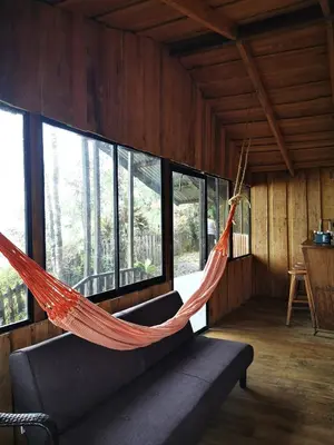 an orange hammock hanging in a room with windows at Rio Paquita Lodge in Tapantí