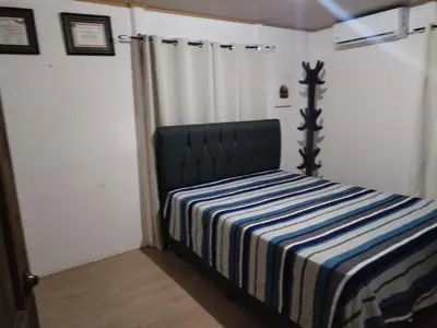 a bedroom with a bed with a striped blanket at Villa Elena Vacation Home in Nicoya