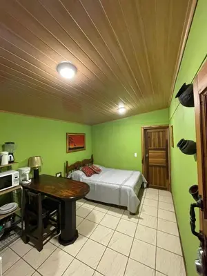 a bedroom with green walls and a bed and a table at Apartamento Norte y Sur in Monteverde Costa Rica