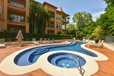 a swimming pool in front of a building at Bella Vista 1C 3 bdrs garden view in Los Suenos in Herradura
