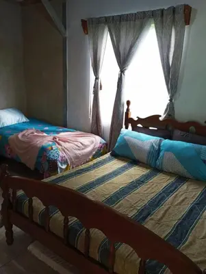 two beds in a room with a window at Hospedaje oye in Herradura