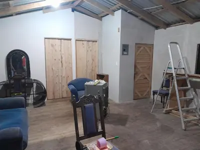 a room with wooden doors and a room with chairs at Hospedaje oye in Herradura
