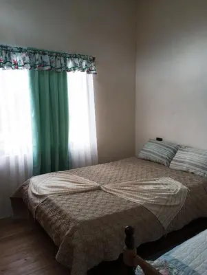 a bedroom with a bed with a green curtain and a window at Hospedaje oye in Herradura