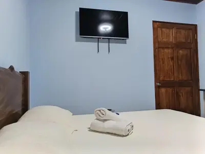 a bed with towels on it with a tv on the wall at Yamis home in General Viejo