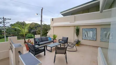 a patio with chairs and a couch on a balcony at La Miraje Villa in Quepos