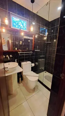 a bathroom with a toilet and a sink and a shower at La Miraje Villa in Quepos