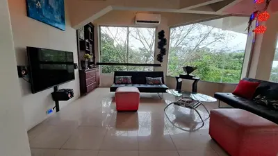 a living room with a couch and a tv at La Miraje Villa in Quepos