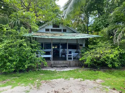 a house with a porch with a chair and trees at Casa de Artistas in Playa Pelada