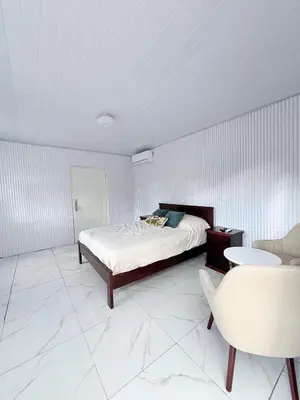 a white bedroom with a bed and a chair at Cabinas Diana in San José Pinilla
