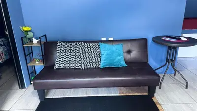 a brown couch with a blue wall and a table at newly remodeled apartment , jaco herradura ,2 cuartos in Herradura