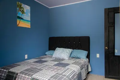a bedroom with a bed with a blue wall at newly remodeled apartment , jaco herradura ,2 cuartos in Herradura