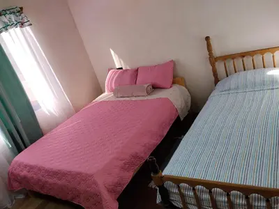 a bedroom with two beds with pink blankets and a window at Hospedaje oye in Rivas