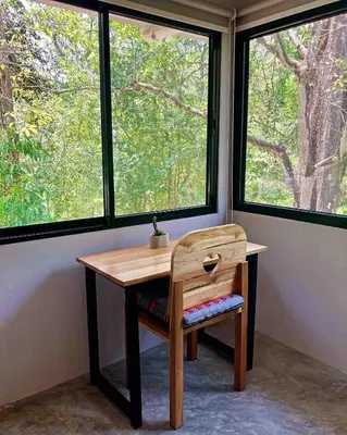 a wooden table and chair in a room with windows at Ital Mountain modern hideaway with tropical vibes in Mal País