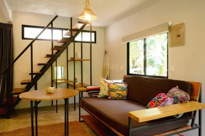 a living room with a couch and a spiral staircase at Ital Mountain modern hideaway with tropical vibes in Mal País