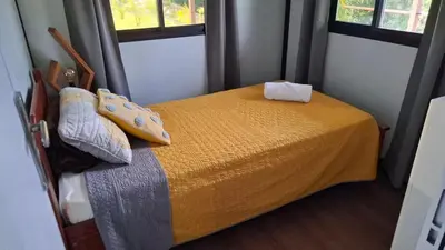 a bedroom with a bed with a yellow blanket and two windows at Casa Loma del Lago - Lake Arenal View in Tilarán