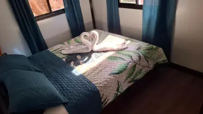 a bedroom with a bed with a blanket and shoes on it at Casa Loma del Lago - Lake Arenal View in Tilarán