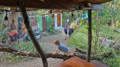 a child sitting on a log in front of a tent at Hostal con camas compartidas - Pachamama Bio in Tamarindo