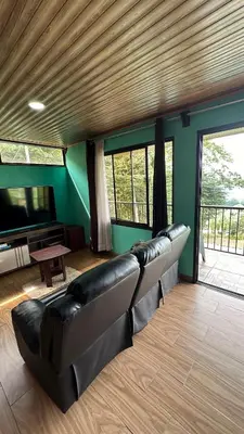 a leather couch in a living room with a television at Villa Solevila in Turrialba