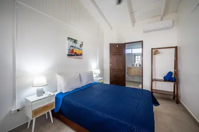 a bedroom with a blue bed in a white room at Ozeano Hotel & Surf Bar in Jacó