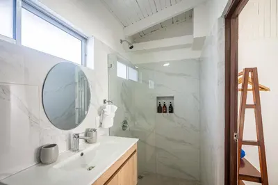 a bathroom with a sink and a mirror and a shower at Ozeano Hotel & Surf Bar in Jacó