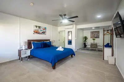 a bedroom with a blue bed and a ceiling fan at Ozeano Hotel & Surf Bar in Jacó