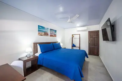 a bedroom with a blue bed and a tv at Ozeano Hotel & Surf Bar in Jacó