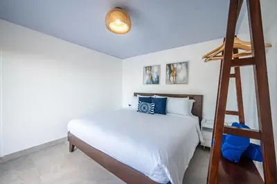 a bedroom with a white bed and a ladder at Ozeano Hotel & Surf Bar in Jacó